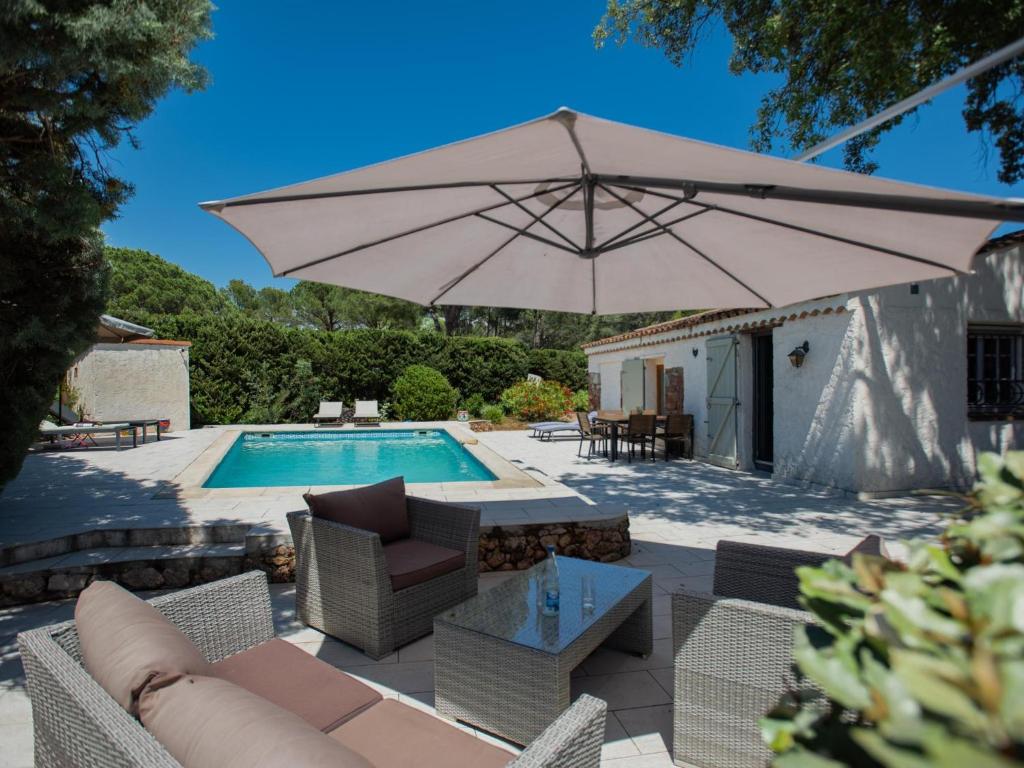 une terrasse avec un grand parasol et une piscine dans l'établissement Pin Parasol, à Roquebrune-sur Argens