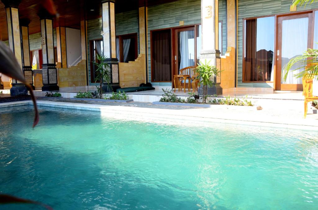 a pool of blue water in front of a building at Bima Sakti House Canggu in Canggu