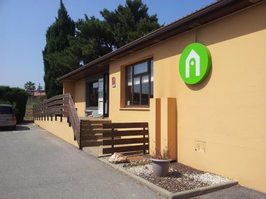 un bâtiment avec un panneau vert sur son côté dans l'établissement Campanile Perpignan Sud, à Perpignan