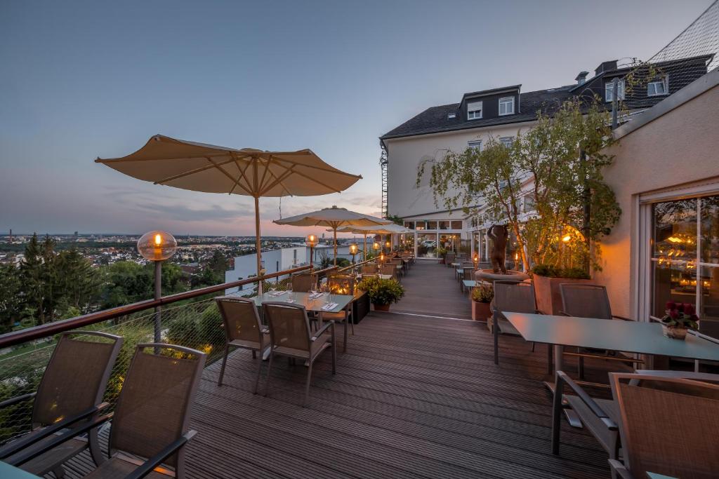 einen Balkon eines Restaurants mit Tischen und Sonnenschirmen in der Unterkunft Hotel Schöne Aussicht in Frankfurt am Main