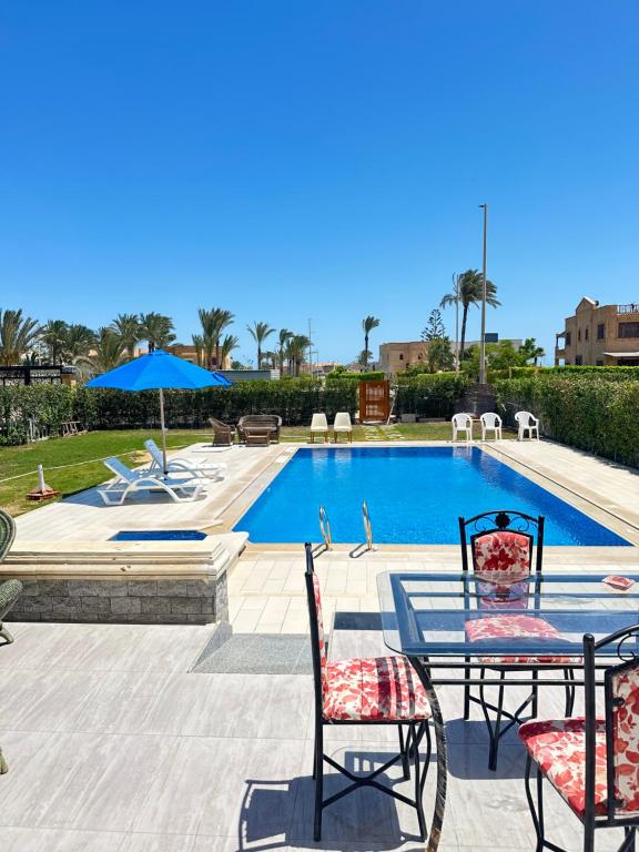 a patio with a table and chairs and a pool at فيلا للإيجار برايفت بول مارينا 5 الساحل الشمالي فيلا 5 غرف نوم مكيف بالكمال فرش فندقي in El Alamein