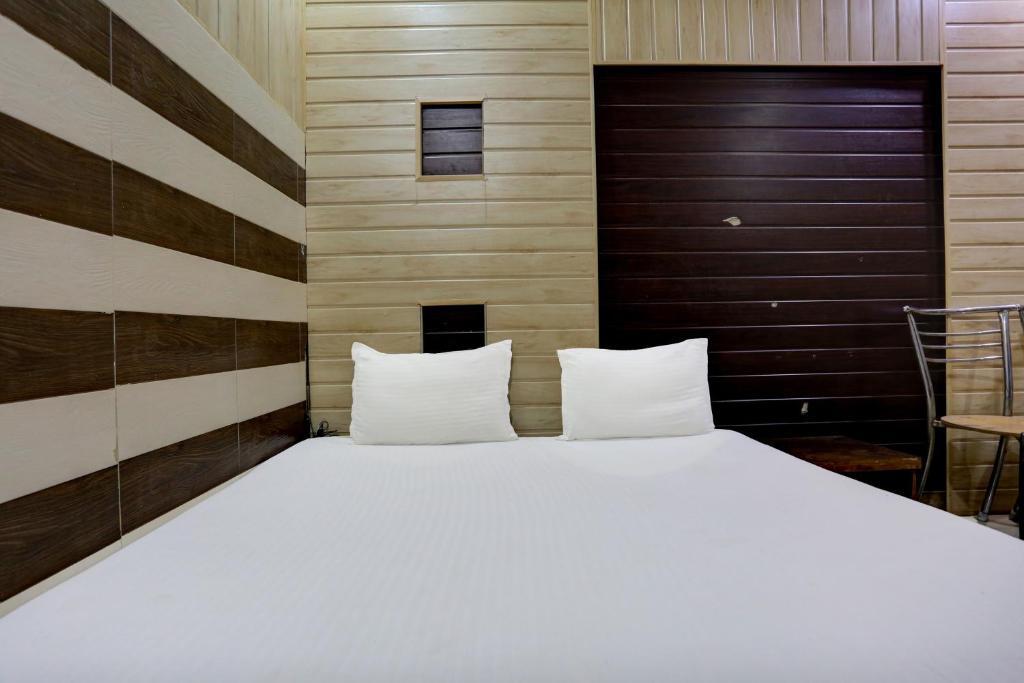 - une chambre avec un grand lit blanc et des murs en bois dans l'établissement OYO Mahadev Guest House, à Kokkíni Khánion