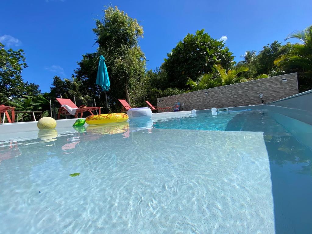 a swimming pool with chairs and an umbrella at Villa Corail Les Abymes in Les Abymes