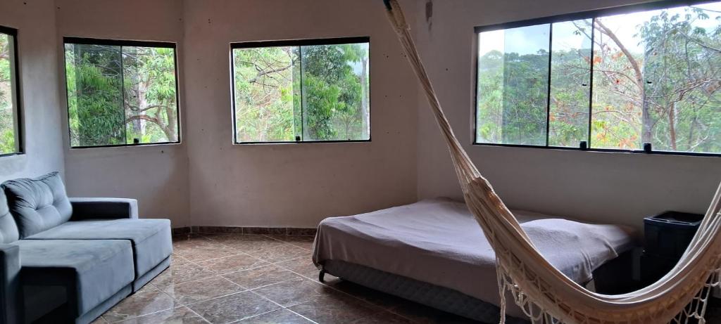 um quarto com uma rede de descanso, uma cadeira e janelas em Camping Guapira em Vale do Capao