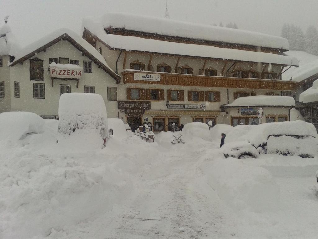 a snow covered street in front of a building at Hotel PORDOI in Arabba