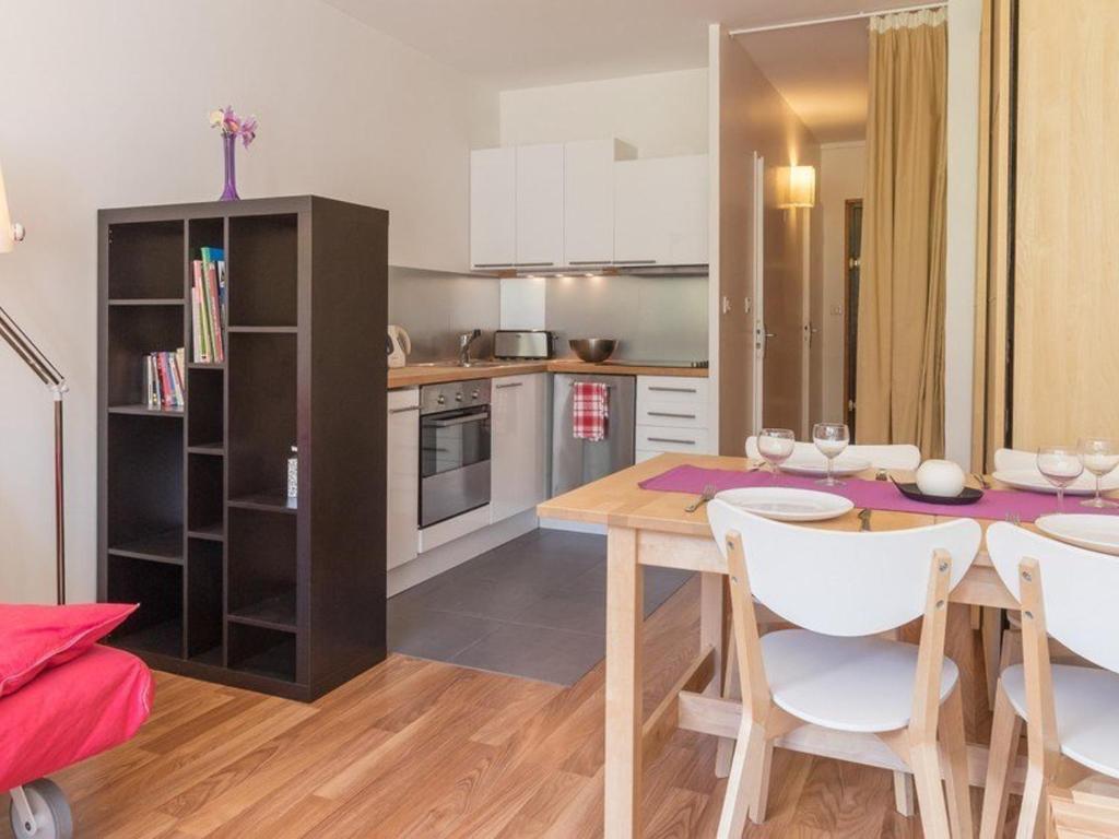 a kitchen with a wooden table and white chairs at Studio rénové avec balcon sud, skis aux pieds, parking et grand jardin, La Salle-les-Alpes - FR-1-330F-237 in La Salle Les Alpes