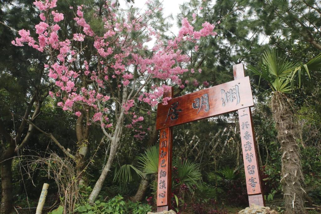 a sign in front of a tree with pink flowers at Alishan B&B YunMinGi in Fenqihu