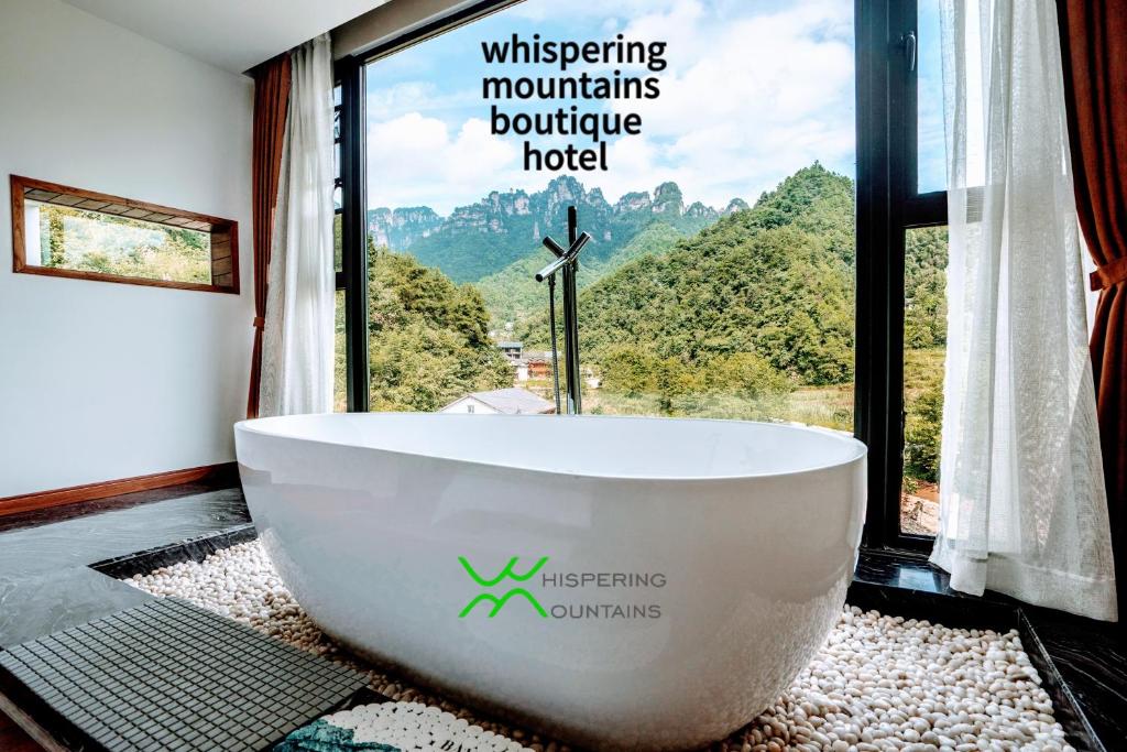 a bathroom with a tub in front of a window at Whispering Mountains Boutique Hotel in Zhangjiajie