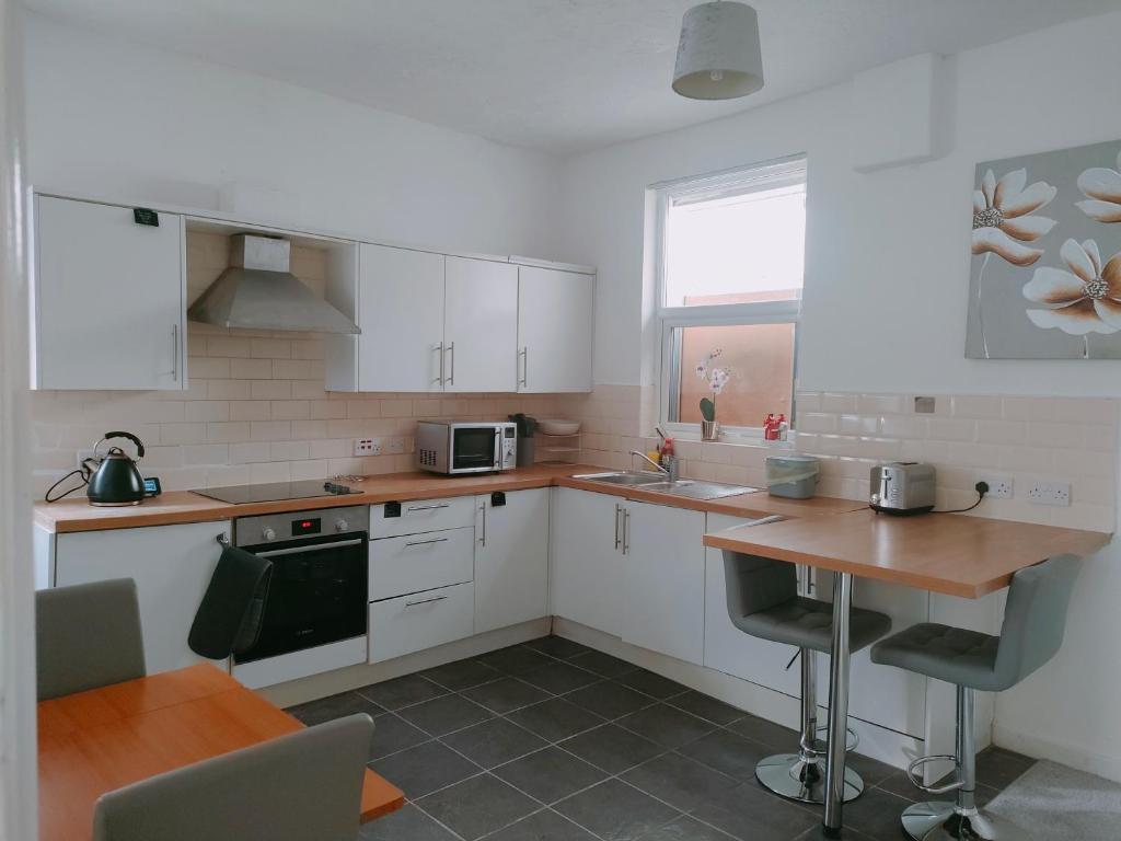 eine Küche mit weißen Schränken und einer Holzarbeitsplatte in der Unterkunft Spacious House, Near Haigh Woodland Park, Wifi, Parking in Leigh