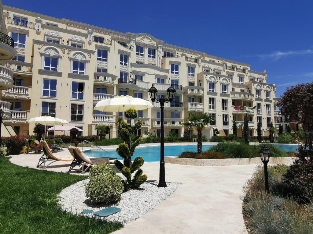 a large apartment building with a pool in front of it at Amber drop with a pool in Ravda