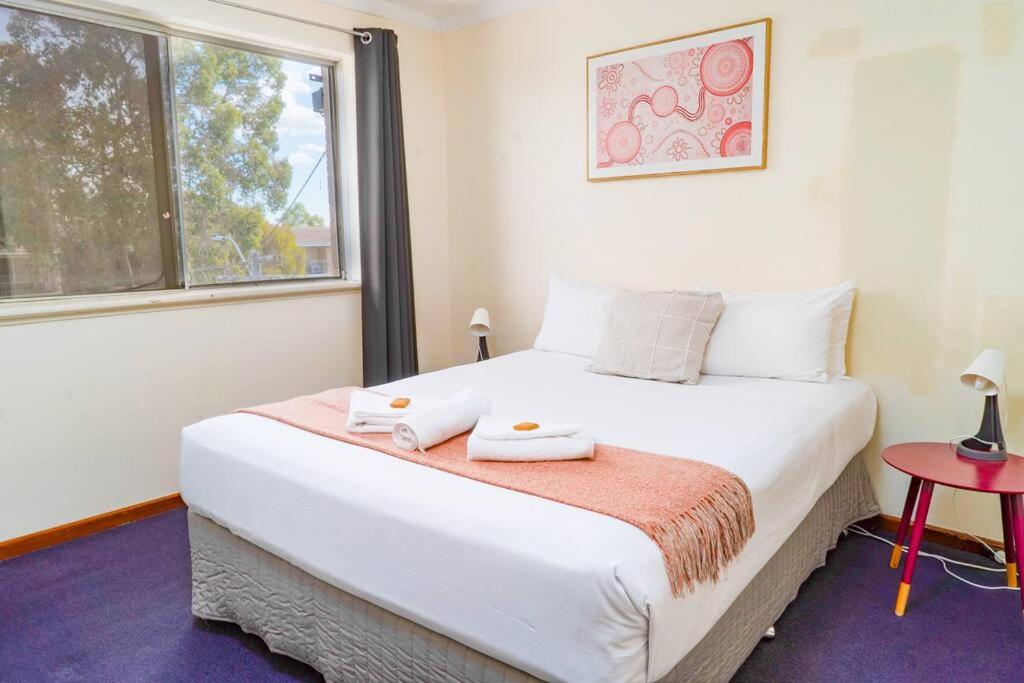 a bedroom with a large white bed with a window at Apartment 9 in Perth