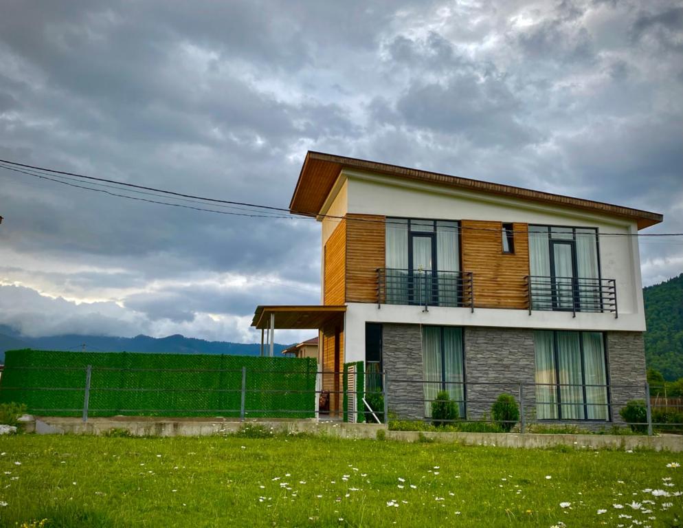 a house with a balcony on top of a field at Cottage Marta Sadgeri in Borjomi