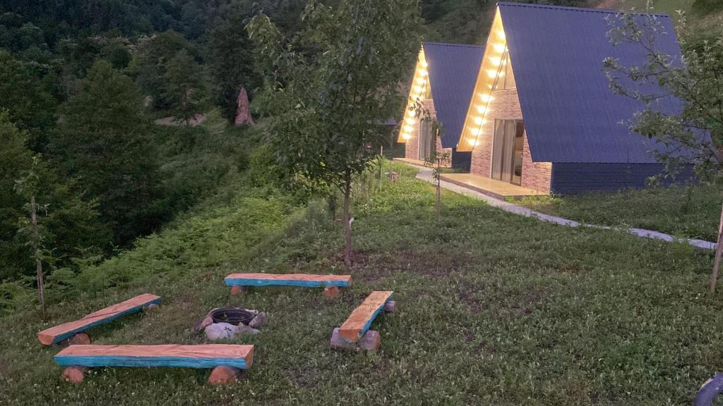 a group of picnic tables in the grass in front of a house at Cottage Merisi inn in Gundauri