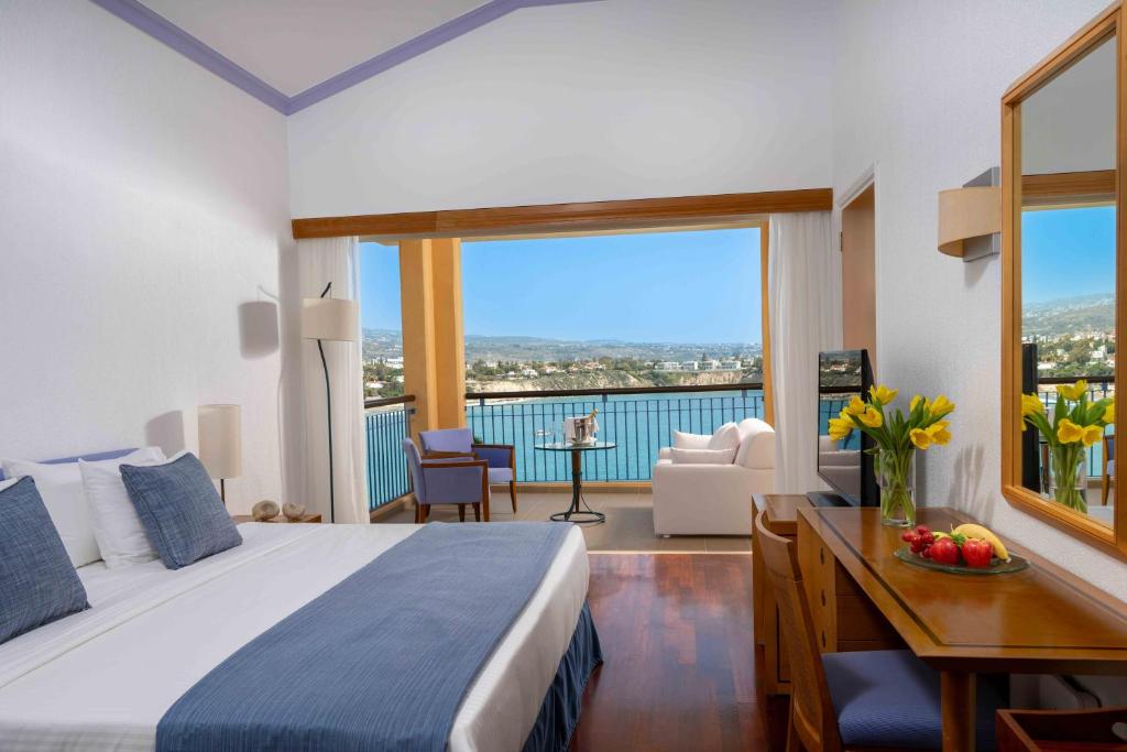 a bedroom with a bed and a desk and a large window at Thalassa Boutique Hotel & Spa in Coral Bay