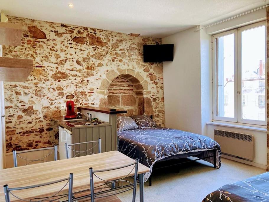 une chambre avec un lit et un mur en pierre dans l'établissement Appartement 1 cosy dans le centre, à Limoges