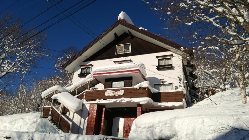 飯山市的住宿－斑尾運動旅館，雪覆盖在雪覆盖的树上的房子