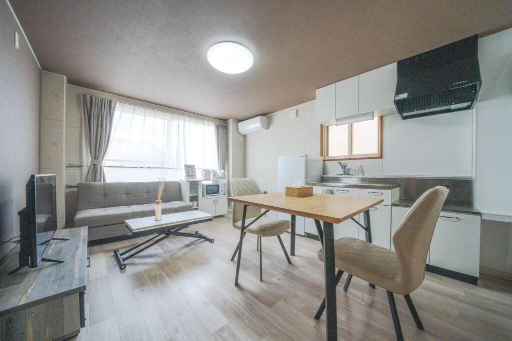 a kitchen and living room with a table and chairs at Guesthouse CoBo in Otaru