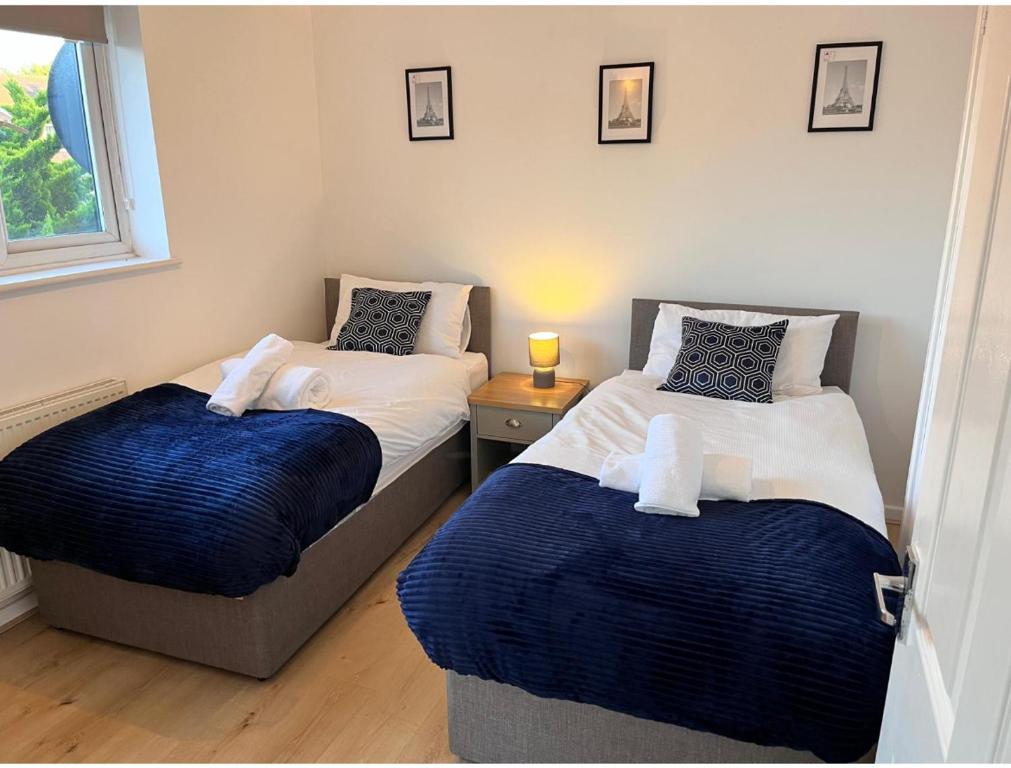 a bedroom with two beds with blue and white sheets at Kettering Service Accomodation 2BRH FreeParking Wifi Smart TV Tea & coffee in Kettering