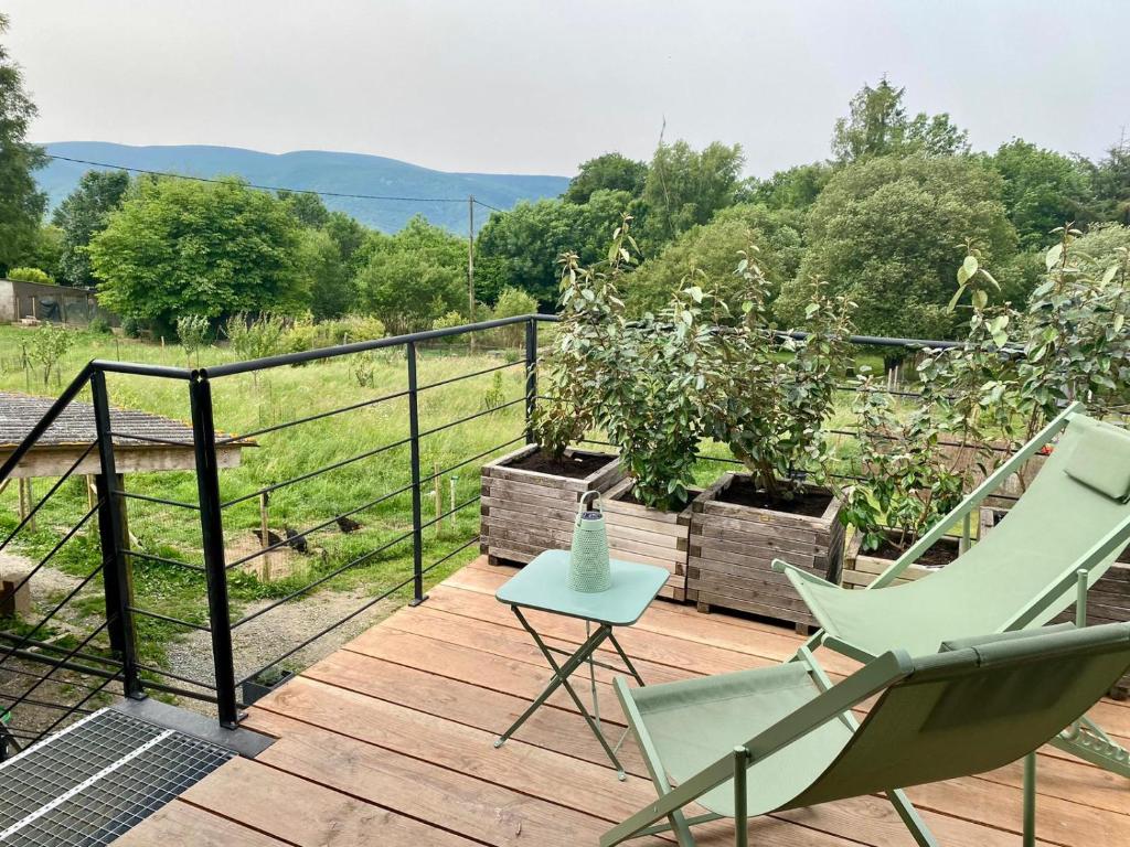 a deck with two chairs and a table on it at Séjour confort et nature in Saint-Amans-Valtoret