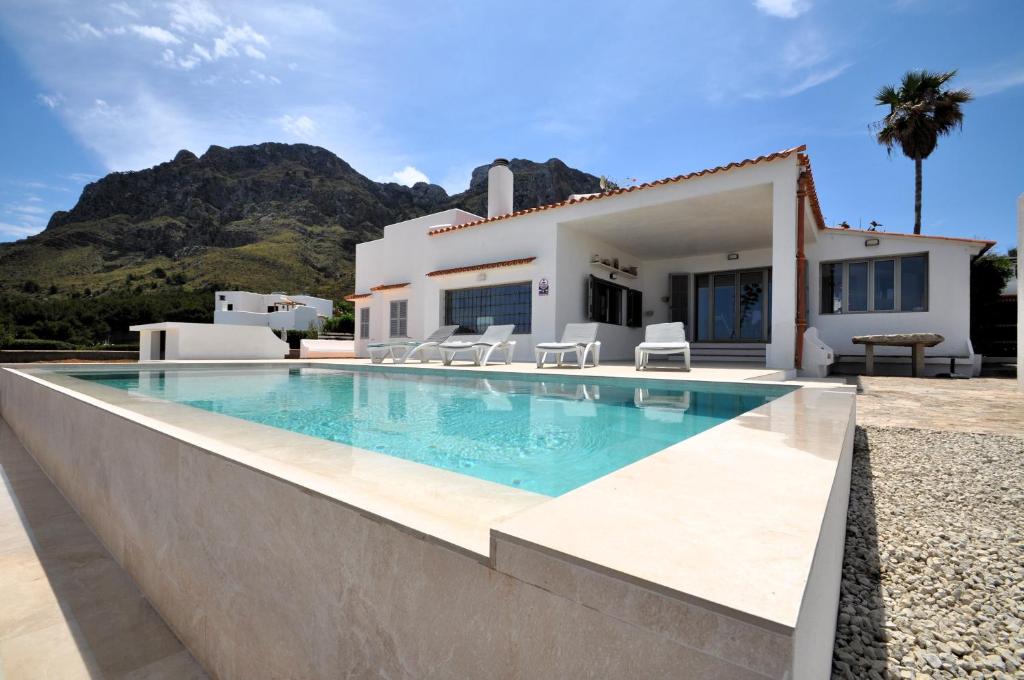 a villa with a swimming pool in front of a house at XOROI- Villa primera linea mar con vistas a Bahía Alcudia in Artá