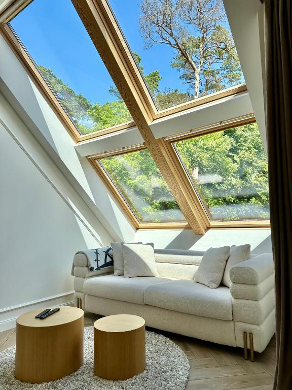 a living room with a skylight and a couch and tables at White Penthouse Juodkrante in Juodkrantė