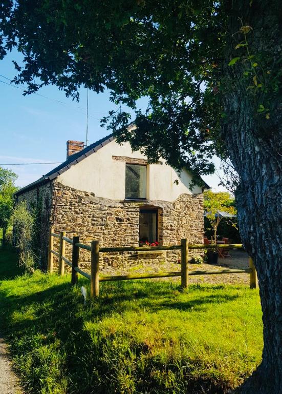 une maison en pierre avec une clôture et un arbre dans l'établissement Pause campagne, à La Chapelle-Bouexic