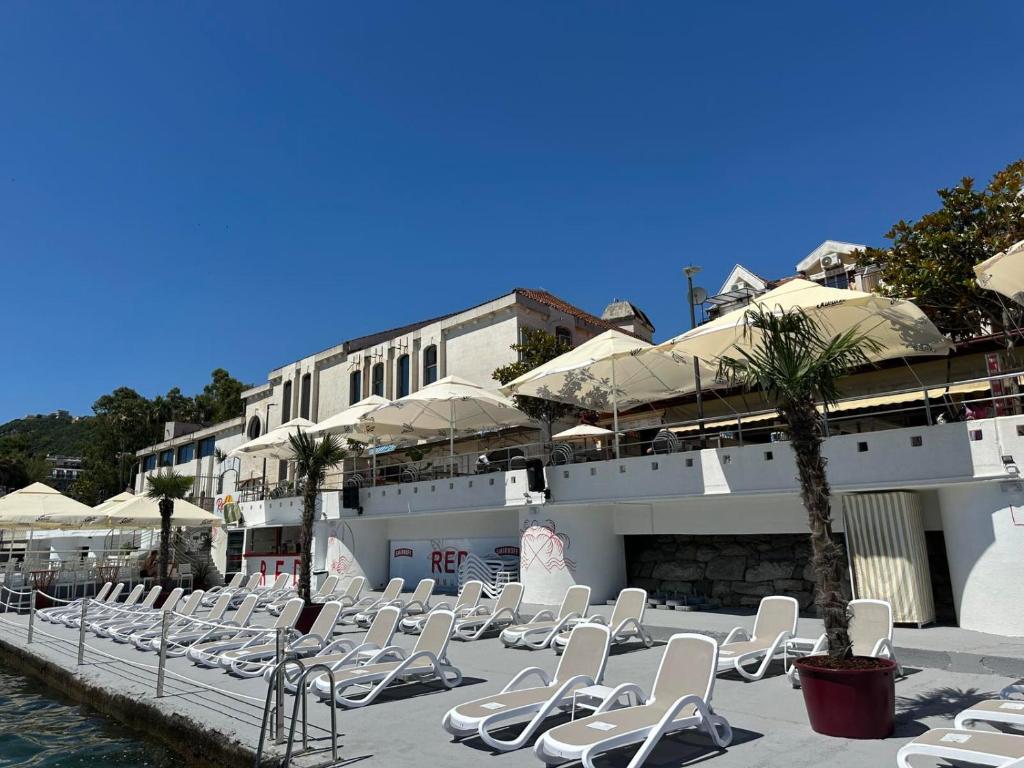 a row of white lounge chairs next to a building at Apartments Sun House in Herceg-Novi
