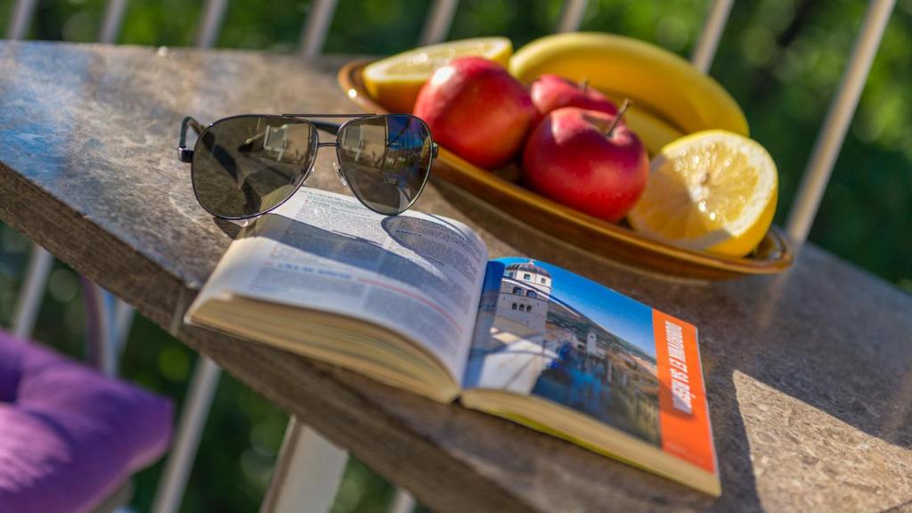 un libro y gafas de sol sobre una mesa con fruta en Family Apartment Bella en Dubrovnik