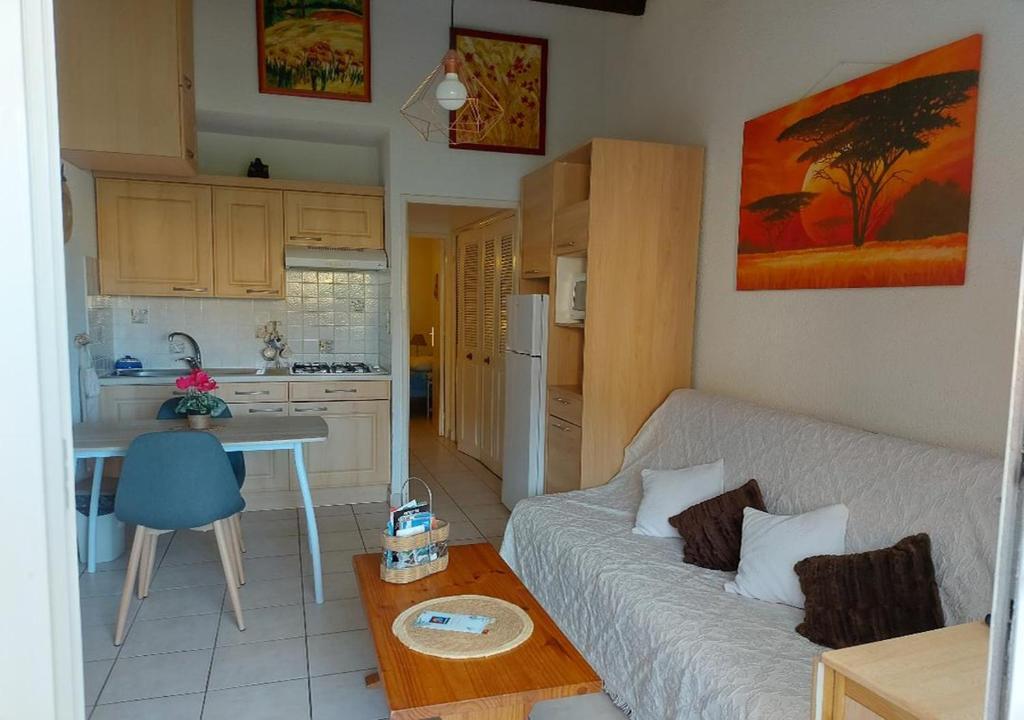 ein Wohnzimmer mit einer weißen Couch und einer Küche in der Unterkunft Cap d'Agde, appartement bord de mer, 50 m plage de la Roquille, climatisé et WIFI, in Cap d'Agde