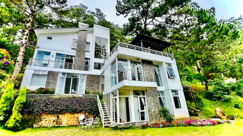ein großes weißes Gebäude mit einer Veranda und einem Hof in der Unterkunft Biệt Thự Lan Anh Đà Lạt in Da Lat