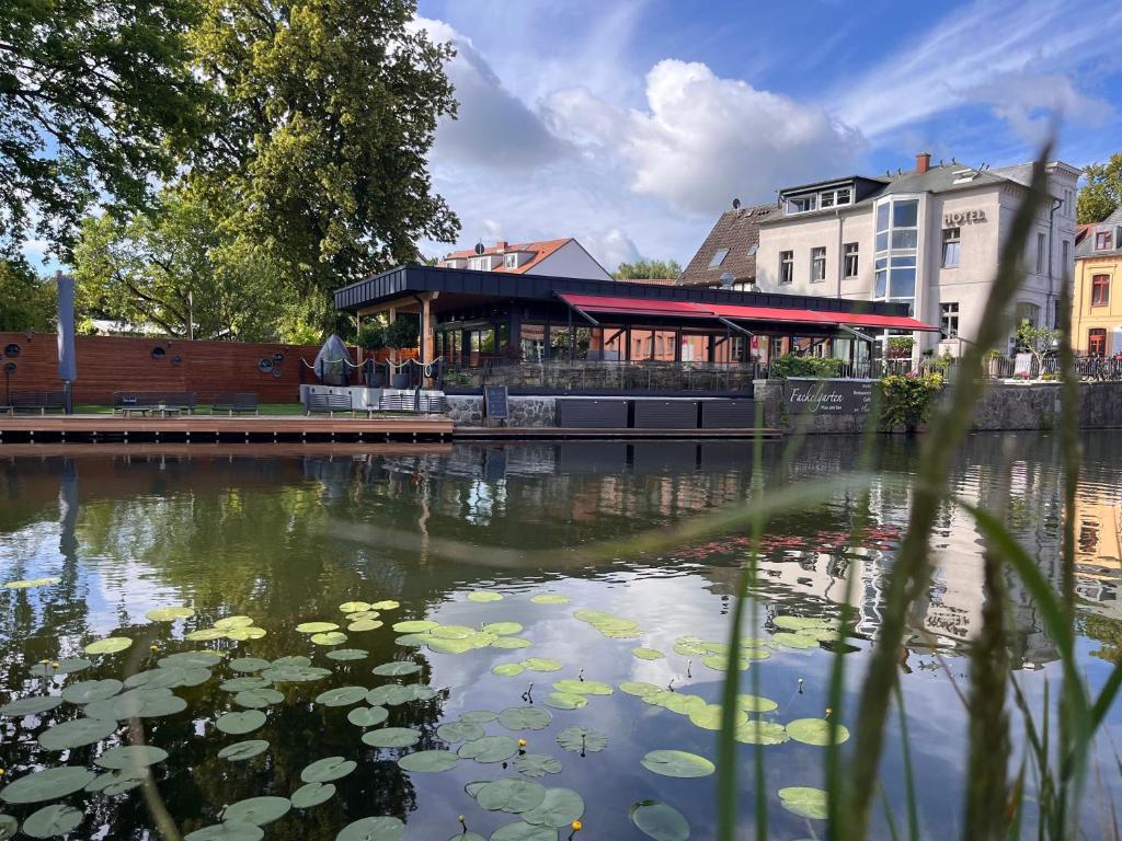 a pond with lily pads in front of a building at Hotel & Restaurant Fackelgarten Plau am See in Plau am See