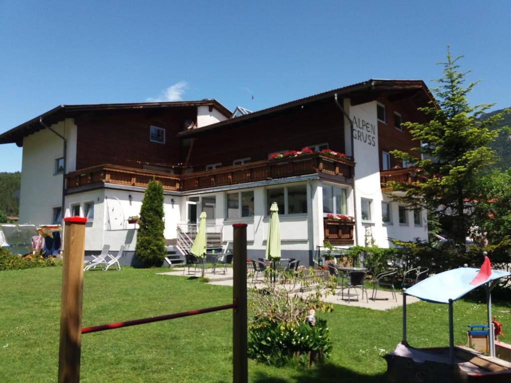 a building with a yard with chairs and umbrellas at Pension Alpengruss in Heiterwang