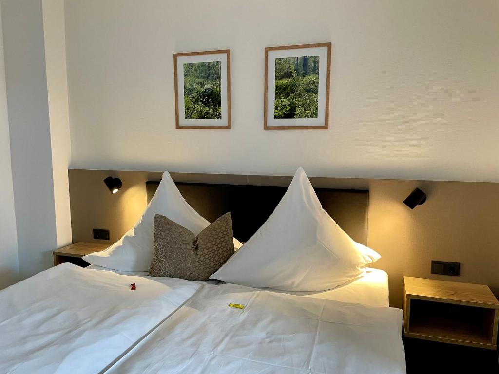 a large white bed with two pictures on the wall at Haus Fliederbusch in Borken