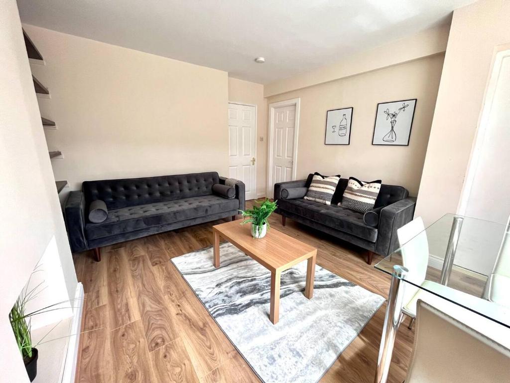 ein Wohnzimmer mit zwei schwarzen Sofas und einem Tisch in der Unterkunft Central 4 Bedroom House With Driveway in Newcastle upon Tyne