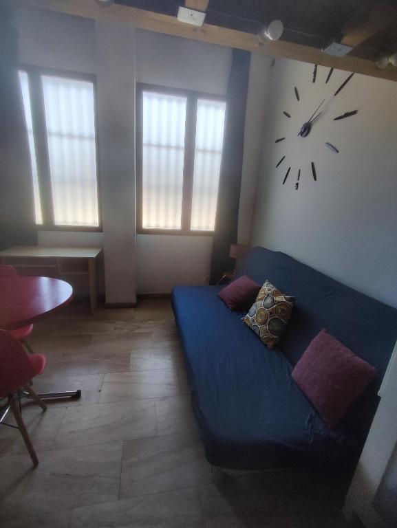 sala de estar con sofá azul y reloj en la pared en Loft duplex industrial near the sea bicicles, en Valencia