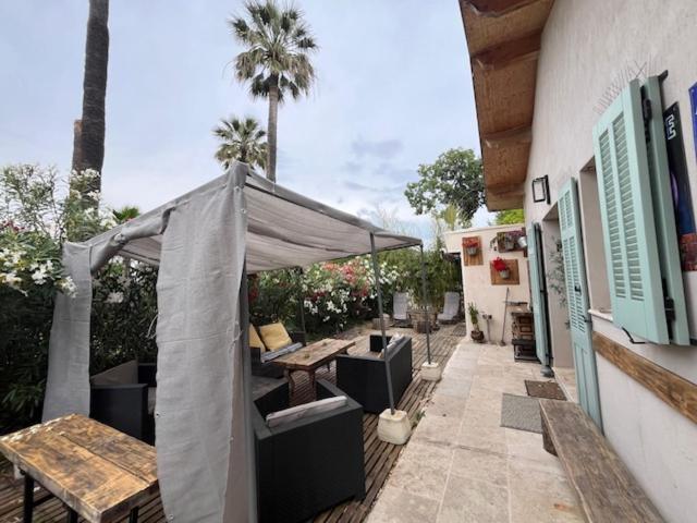 une terrasse avec une tente, une table et des bancs dans l'établissement Bel appartement dans une maison, à Cannes