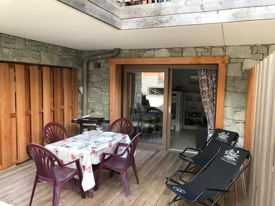 une table à manger et des chaises sur un porche avec un mur en pierre dans l'établissement Les 4 éléments C004 - Multipass inclu, à Châtel