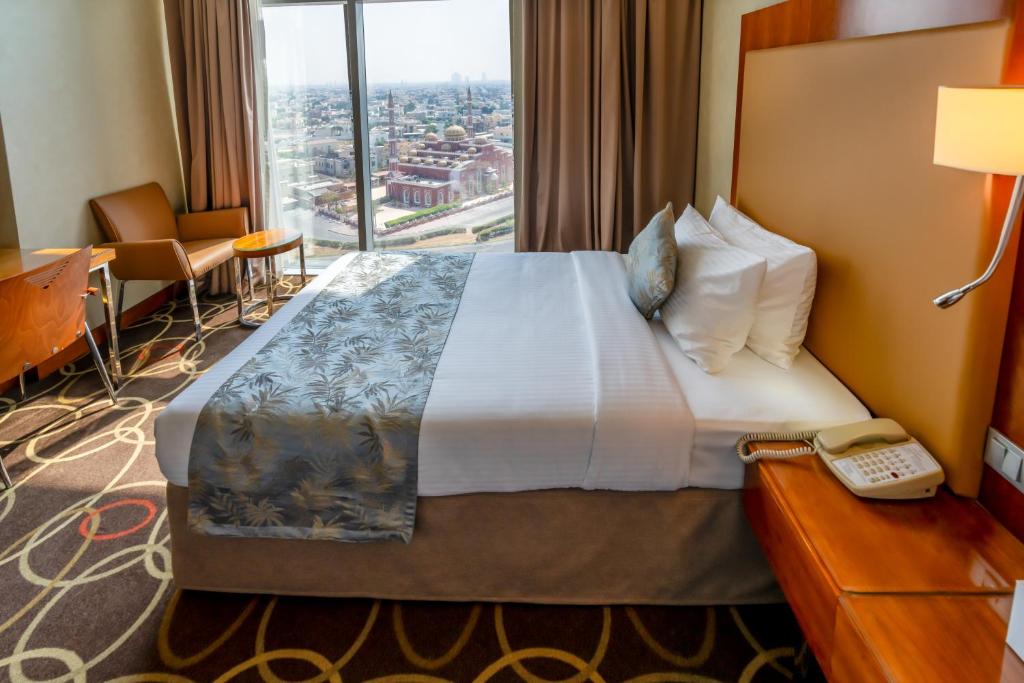 Habitación de hotel con cama con teléfono y ventana en Montreal Barsha Hotel en Dubái