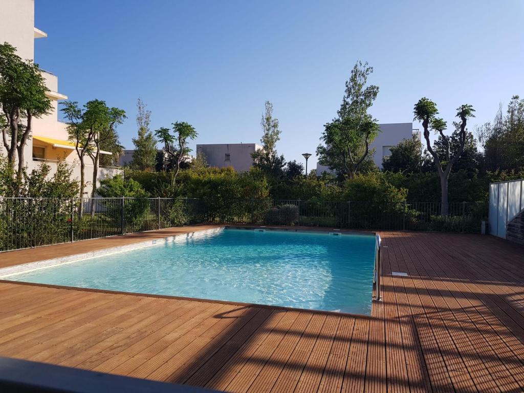 - une piscine dans une cour avec une terrasse en bois dans l'établissement Studio à la mer avec piscine, à Sète