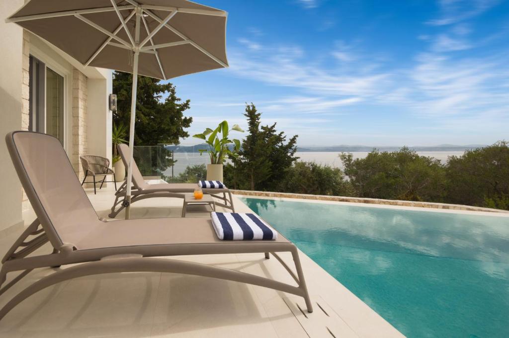 a chair with an umbrella next to a swimming pool at Villa Vilielmini Paxos in Gaios