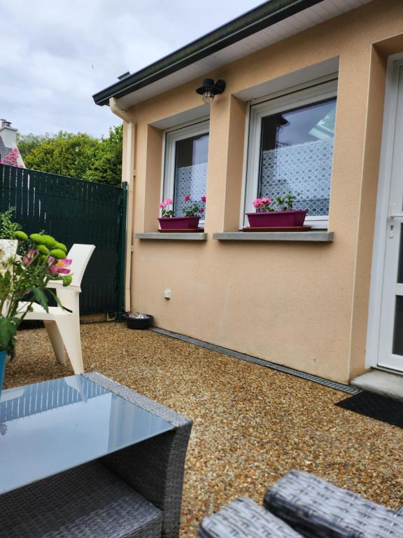 un patio avec une table en verre et deux fenêtres dans l'établissement Gîte des dolmens 3 etoiles, à Saint-Quay-Portrieux