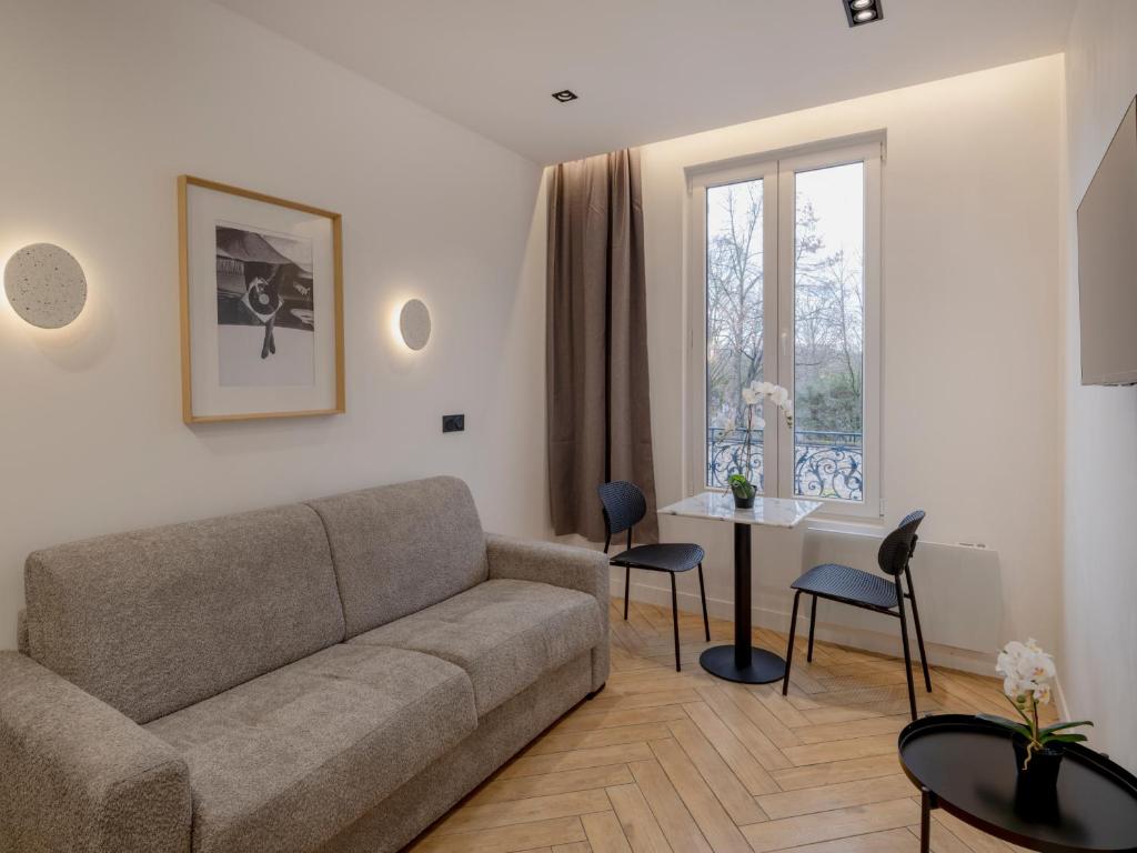 un salon avec un canapé, une table et une fenêtre dans l'établissement Pretty Studio in Pantin, à Pantin