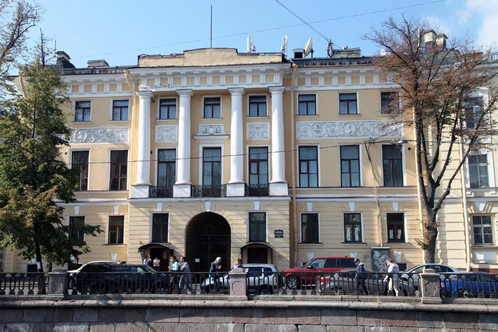 a large white building with cars parked in front of it at Hotel Park Lion Bridge in Saint Petersburg