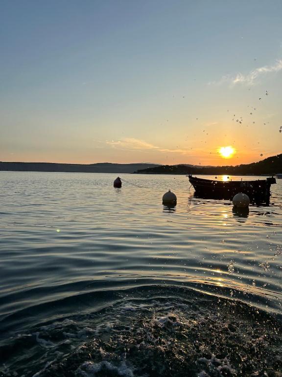 a boat sitting in the water at sunset at Nona - 200m from the beach in Jadranovo