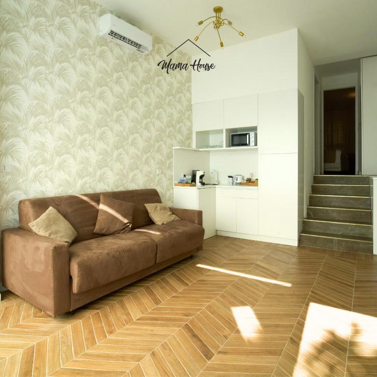 a living room with a brown couch and a staircase at Mama House Cenisio in Milan