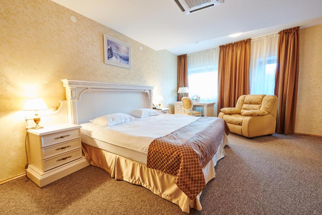 a bedroom with a large bed and a chair at Victoria Hotel na Zamkovoy Minsk in Minsk