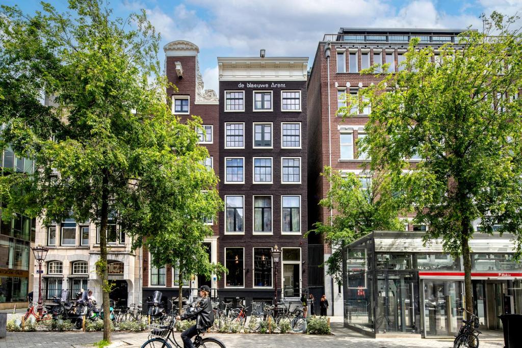 a man riding a bike in front of a building at Mister Highland Hotel in Amsterdam