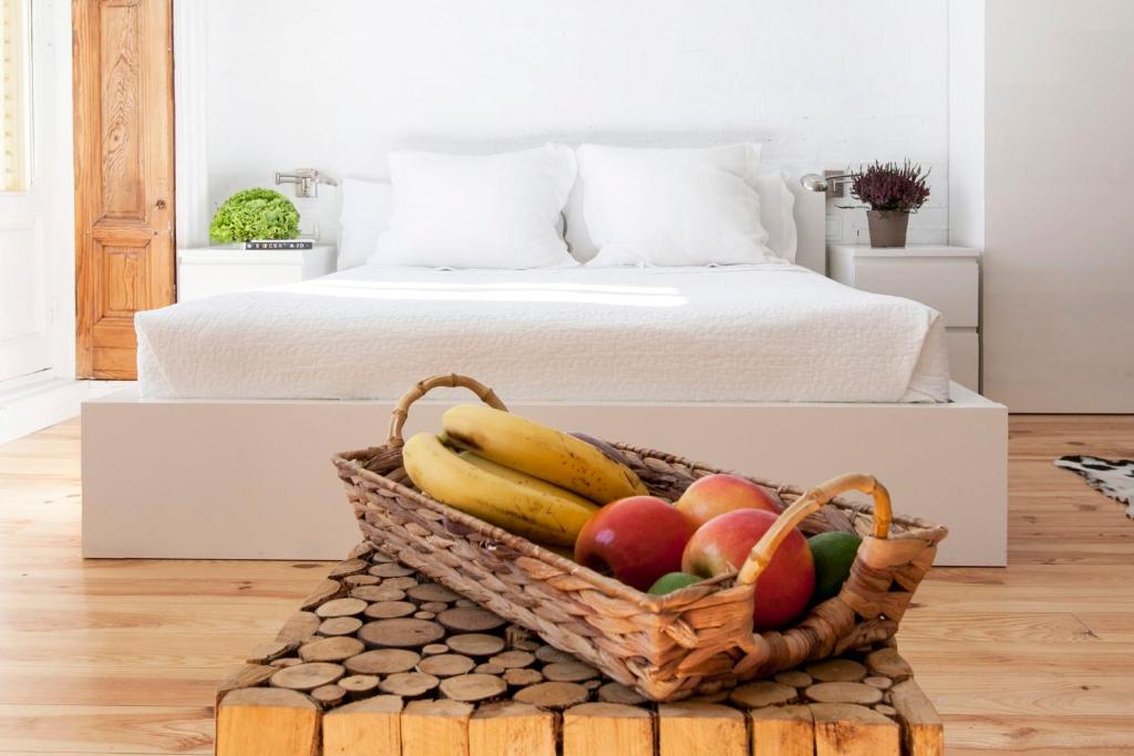 una cesta de fruta en una mesa junto a la cama en Apartamentos Matute 11, en Madrid