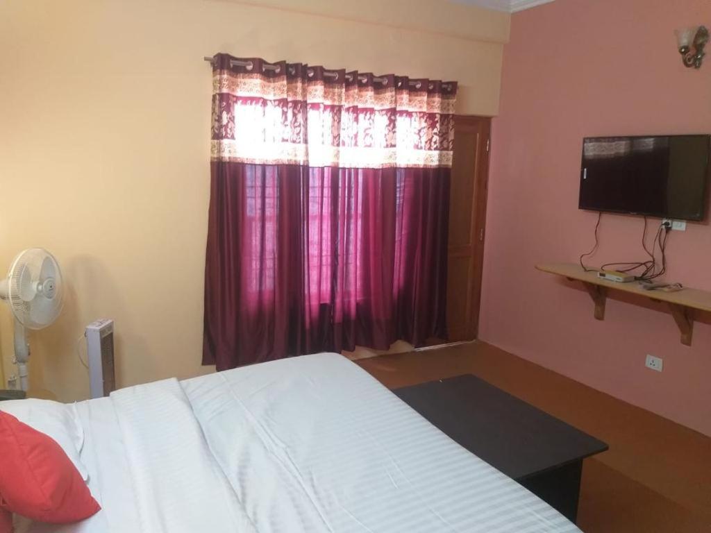 a bedroom with a bed and a window with purple curtains at Prestige Villa in Shimla