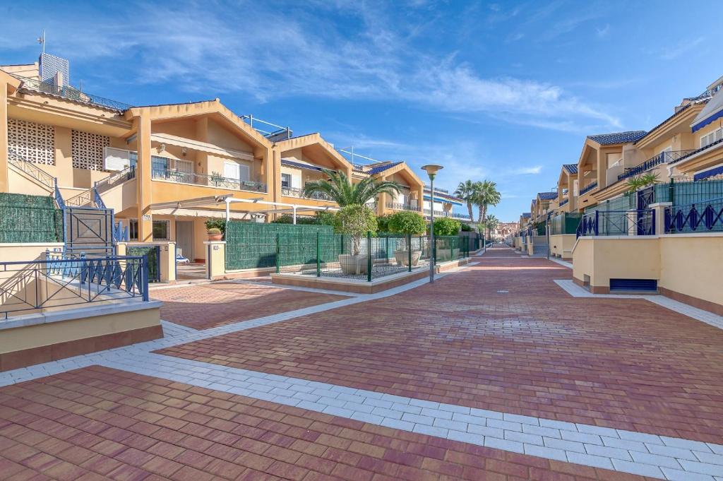 a brick street with houses and palm trees at Lux de Novamar en Gran Alacant in Puerto Marino